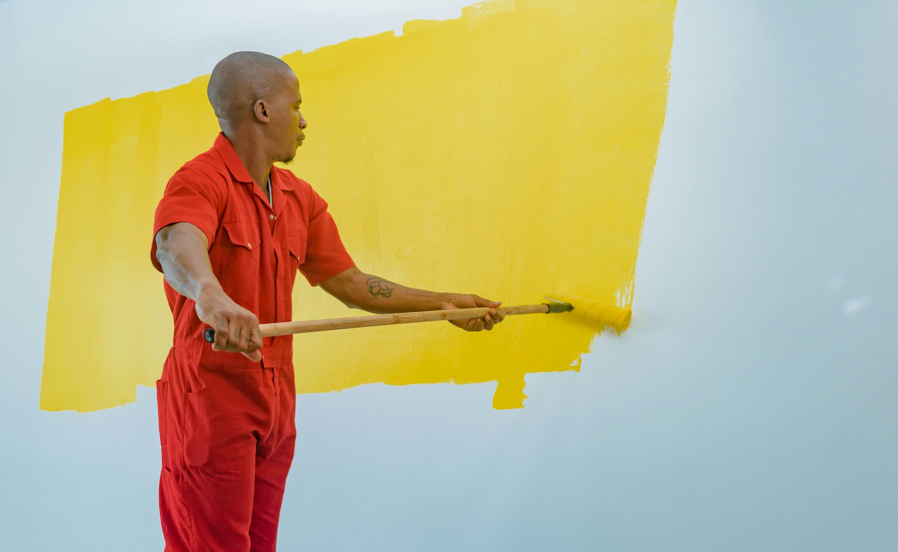 Peintre appliquant une peinture jaune au rouleau sur un mur