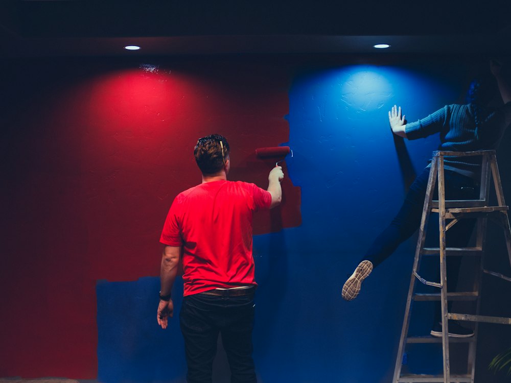 Deux peintres repeignant une pièce en rouge et bleu